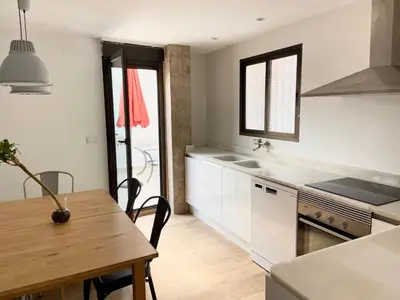 a kitchen with white cabinets and a wooden table with a wooden table sidx sidx sidx at Apartamento artístico en el centro de Segorbe in Segorbe