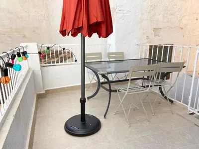 a glass table and a red umbrella on a balcony at Apartamento artístico en el centro de Segorbe in Segorbe