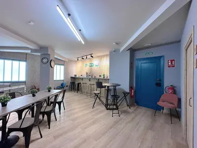 a room with tables and chairs and a blue door at The POD Suite Hostel Blasco in Valencia