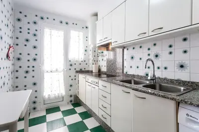 a kitchen with white cabinets and a green and white checkered floor at Alquiler de temporada Canet Playa - en primera linea in Canet de Berenguer