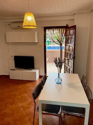 a living room with a table and chairs and a television at Sol y Mar in Puebla de Farnals