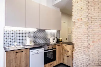 a kitchen with white cabinets and a brick wall at Charming and Comfortable Apartment with Inviting Atmosphere in Valencia