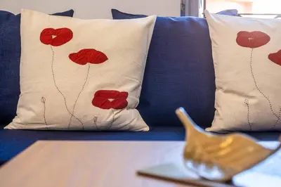a blue couch with pillows with red poppies on it at BrightHouse with Warm and Friendly Vibes in Valencia