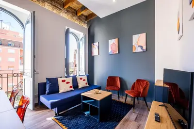a living room with a blue couch and two red chairs at BrightHouse with Warm and Friendly Vibes in Valencia