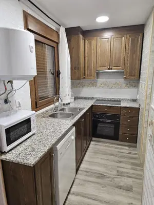 a kitchen with wooden cabinets and a sink and a microwave at EL ARA DE LOS ORISHAS in Siete Aguas