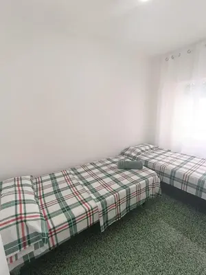 two beds in a room with white walls at Apartamento Lyon in Cullera