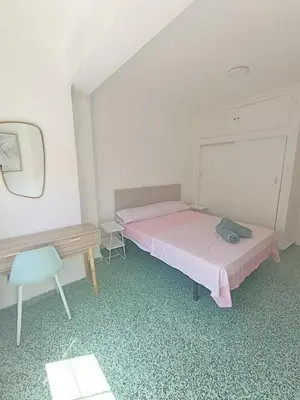 a bedroom with a bed and a desk and a mirror at Apartamento Lyon in Cullera