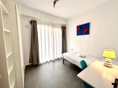 a small room with a bed and a table with a lamp at Malvarrosa Beach in Valencia