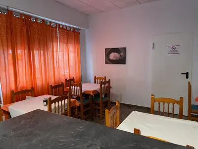 a dining room with tables and chairs and orange curtains at Albahicín in Puerto de Sagunto