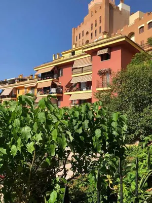 a red building with trees in front of it at comfortable apartment in an elite area with a beautiful veranda in Port Saplaya
