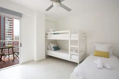 a white bedroom with a bunk bed and a table at SingularStays Cullera V in Cullera