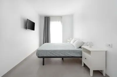 a white bedroom with a bed and a white night stand at Vilamercat in Sueca