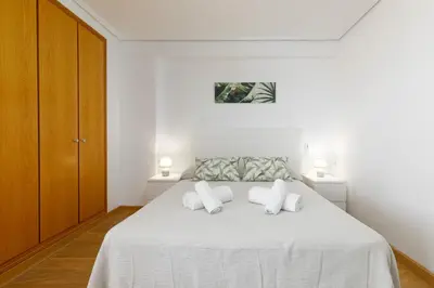 a white bedroom with a bed with white pillows at ApartUP Patacona Surfing Beach in Valencia