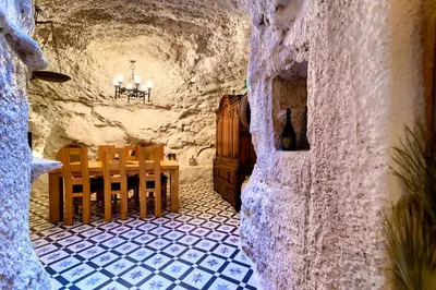 a restaurant with a table and chairs in a stone room at Cueva con jacuzzi a 20 minutos de Valencia in Benaguacil