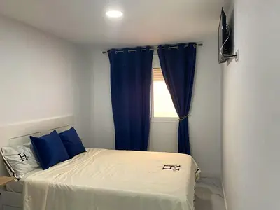 a bedroom with a bed with blue curtains and a window at Your Perfectt place in Valencia