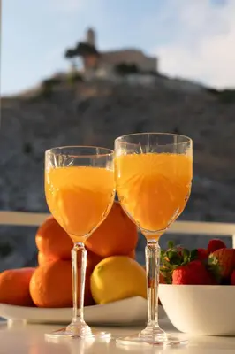 two glasses of orange juice on a table with fruit at Apartamento mar&menta in Cullera