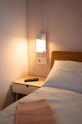 a bedroom with a bed and a night stand with a lamp at La Siesta Hostel in Almarda