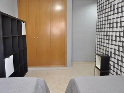 a bedroom with two beds and a wooden cabinet at Acogedor apartamento en Burriana centro in Burriana
