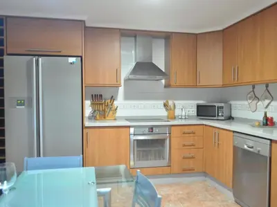 a kitchen with stainless steel appliances and wooden cabinets at Acogedor apartamento en Burriana centro in Burriana