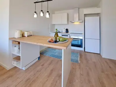 a kitchen with a table with a bottle of wine at Charming flat close to the beach in Canet de Berenguer