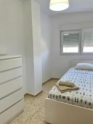 a white bedroom with a bed and a dresser at UIM Mediterraneo Emilio Llopis Wifi in Sagunto