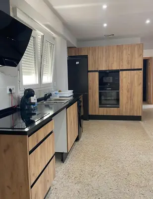 a kitchen with wooden cabinets and a black refrigerator at UIM Mediterraneo Emilio Llopis Wifi in Sagunto