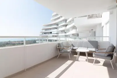 a balcony with chairs and a table on a building at Global Vacacional, Nuevo apartamento con terraza en Gran Canet Residencial in Canet de Berenguer