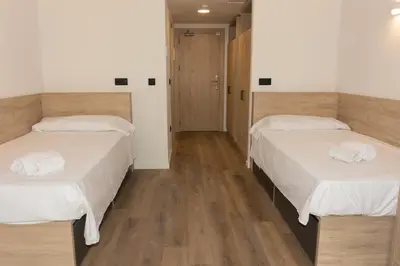 two beds in a room with wooden floors at Micampus Burjassot Parque Student Residence in Burjasot