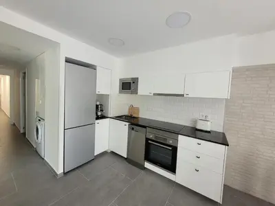 a kitchen with white cabinets and a black counter top at New and Bright 2-bedroom apartment in Cañamelar in Valencia