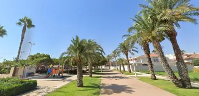 a pathway with palm trees and a playground at V&M Canet in Canet de Berenguer