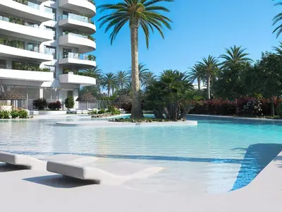 a swimming pool in front of a building with palm trees at Apartment Gran Canet by Interhome in Canet de Berenguer