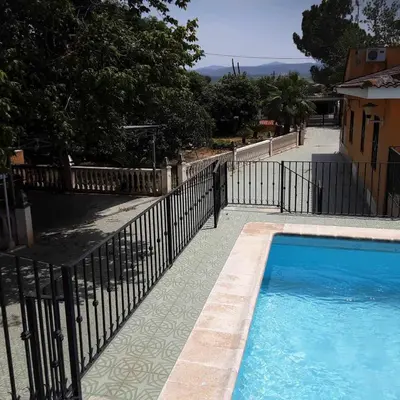 a swimming pool with a fence next to a house at Villa les palmiers in Rafelguaraf
