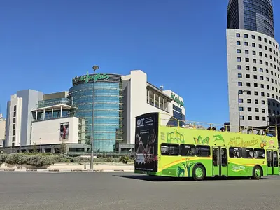 a yellow and green bus parked in front of buildings at Apartamentos Las Ciencias D in Valencia