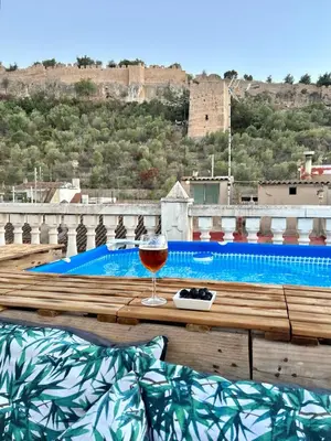 a glass of wine sitting on a table next to a swimming pool at Casa con jacuzzi y piscina con vistas al castillo in Corbera de Alcira