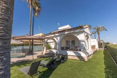a small white house with chairs and an umbrella at Exquisita Villa Frente al Mar in Sagunto