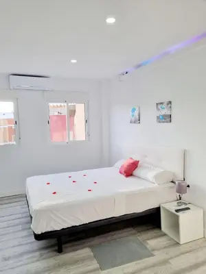 a white bedroom with a large bed with red accents at Apartamentos T5 Valencia in Torrent