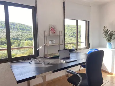 a desk with a laptop on it in a room with windows at Remote Work in Spanish Mediterranean Countryside in Vall de Almonacid