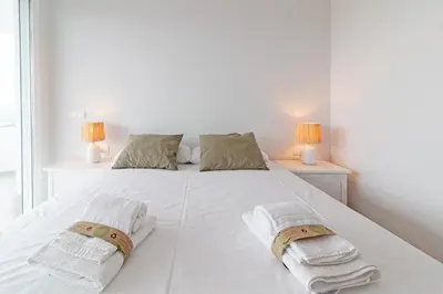 a bedroom with a white bed with two lamps at Global Vacacional, Apartamento con vistas al mar, 2 terrazas y piscina en Canet d'en Berenguer in Canet de Berenguer