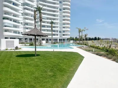 a large apartment building with a swimming pool and a lawn at Global Vacacional, Apartamento con vistas al mar, 2 terrazas y piscina en Canet d'en Berenguer in Canet de Berenguer