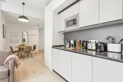 a kitchen with white cabinets and a dining room at Limehome Valencia Calle de Cadiz in Valencia