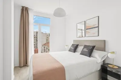 a white bedroom with a large bed and a window at Limehome Valencia Calle de Cadiz in Valencia