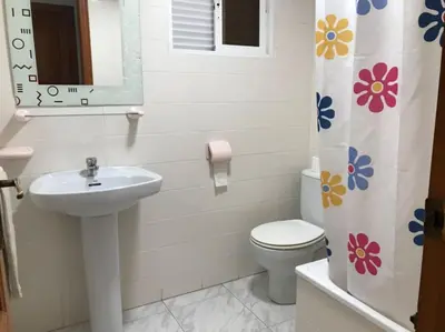a bathroom with a sink and a toilet and a mirror at Casa adosada junto a la playa de El Perelló in Sueca