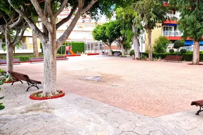 a park with benches and a tree in a courtyard at Bonito apartamento con vistas al mar in Playa Pobla de Farnals