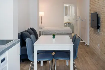 a living room with a white table and blue chairs at VLC HOST- Fray Pedro in Valencia