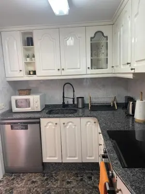 a kitchen with white cabinets and a sink at Apartamento en complejo residencial con piscina y garaje a 100m del mar in Las Canteras