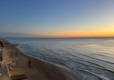 a beach with chairs and the ocean at sunset at Apartamento Rey I in Valencia