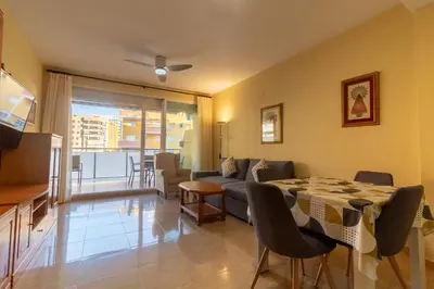a living room with a table and a couch at Global Vacacional, Piso práctico, con terraza y piscina en la playa de Canet in Canet de Berenguer