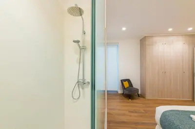 a bedroom with a shower and a bed and a chair at Torres de Serranos Apartments - TTdSSa VLC in Valencia