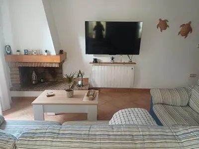 a living room with a couch and a tv on the wall at Adosado/casa con terraza y buhardilla. Playa El Perelló in El Perelló