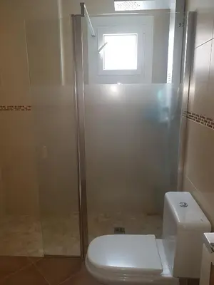 a bathroom with a shower and a toilet and a window at Adosado/casa con terraza y buhardilla. Playa El Perelló in El Perelló